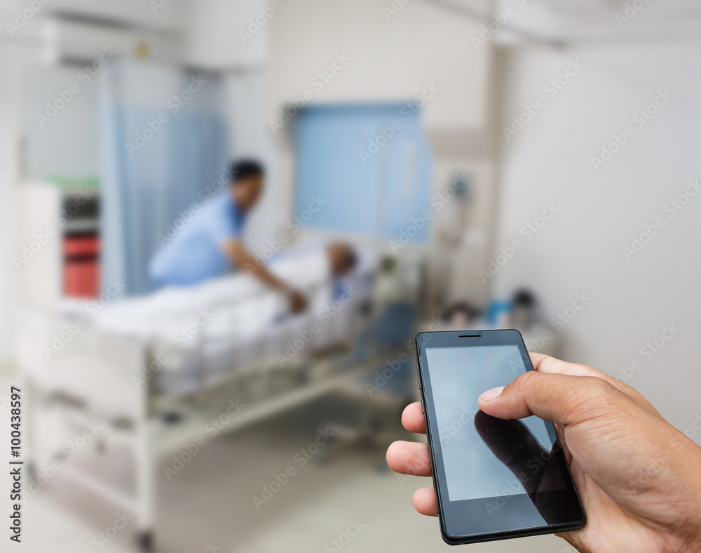 Hand hold and touch screen smart phone, tablet,cellphone on blur image of A patient in the hospital with saline intravenous, in Asian elderly man hand.