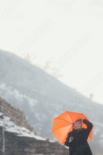 Young woman standing at the hill holding umbrella 