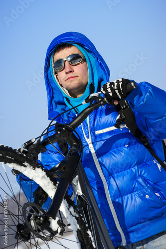 Photography Extreme winter cyclist portrait, bicyclist in sunglasses and jacket with mountai