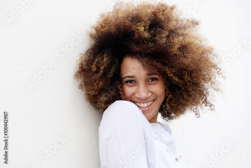 Young woman smiling with afro hair against white background