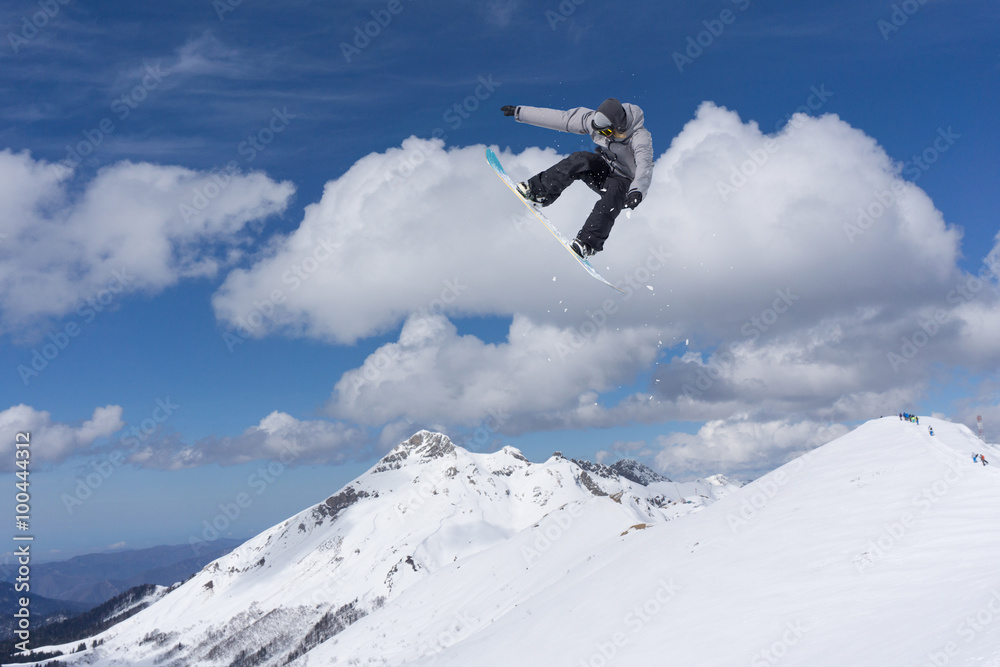 Flying snowboarder on mountains. Extreme sport.