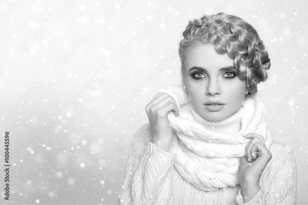portrait of a beautiful young blonde woman on a light background. hair tied in a braid. girl wearing a warm sweater and scarf. copy space..