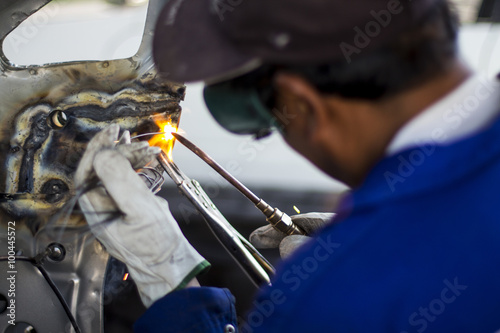 Man mechanical worker repairing a car body in a garage