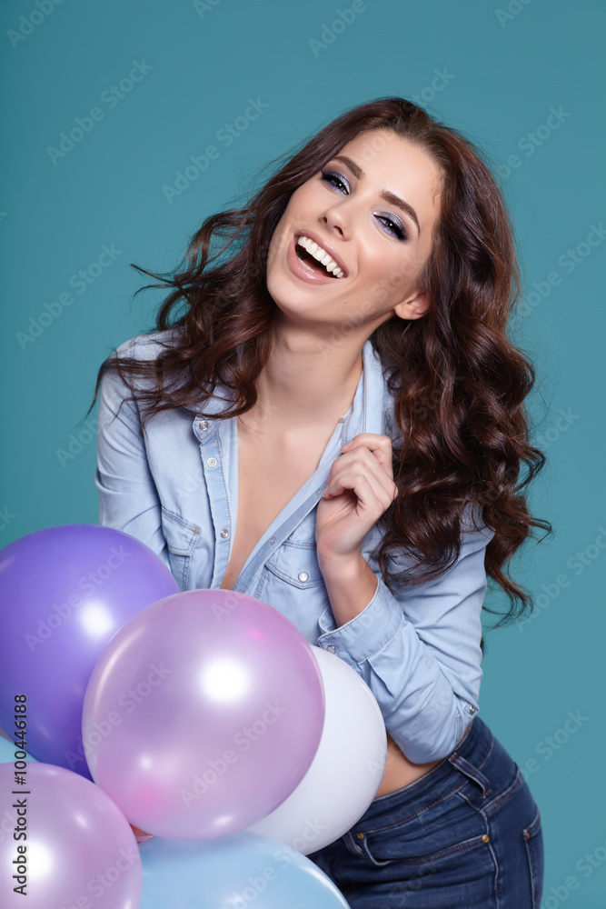 Happy young woman standing over blue wall and holding pink and w Happy young woman standing over blue wall and holding pink and w