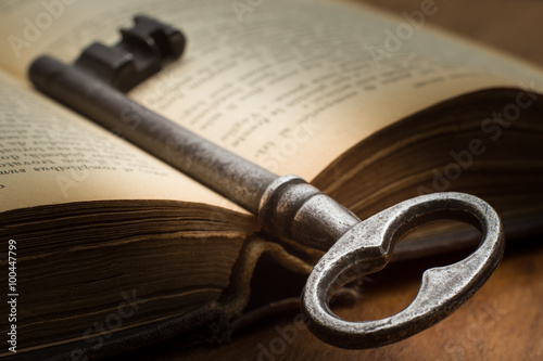 A key and an open old book - Una chiave e un vecchio libro aperto photo
