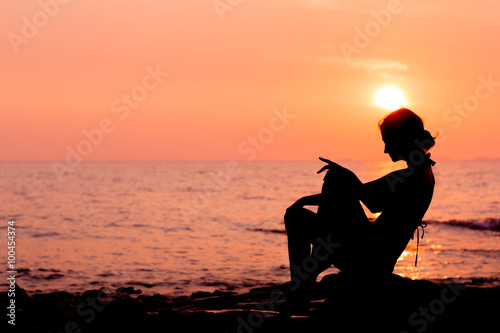 Woman silhouette sitting on sunset sea background, side view, back lit © whiteandlight.com
