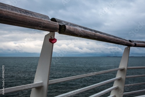 Old handrail against north sea with lock in form of heart.