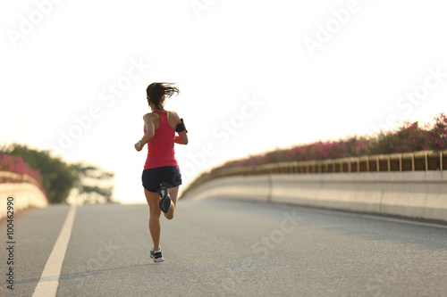 young woman runner running on city bridge road