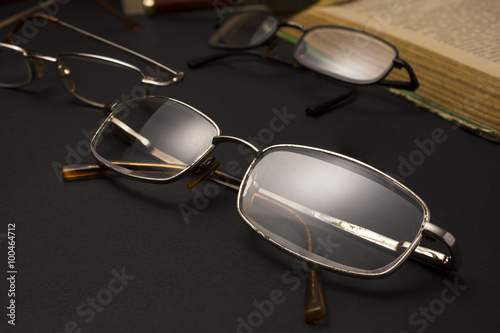 Eyeglasses with magnifying glass on dark surface with books. High resolution image design for Ophthalmologist concept.