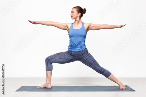 Woman practices yoga asana utthita Virabhadras
