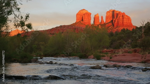 Cathedral Rock glowing red-orange reflecting the last rays of the sun, with Oak Creek in the foreground; Sedona, Arizona.