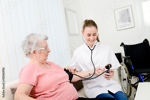 elderly senior woman with a young doctor having medical care at home