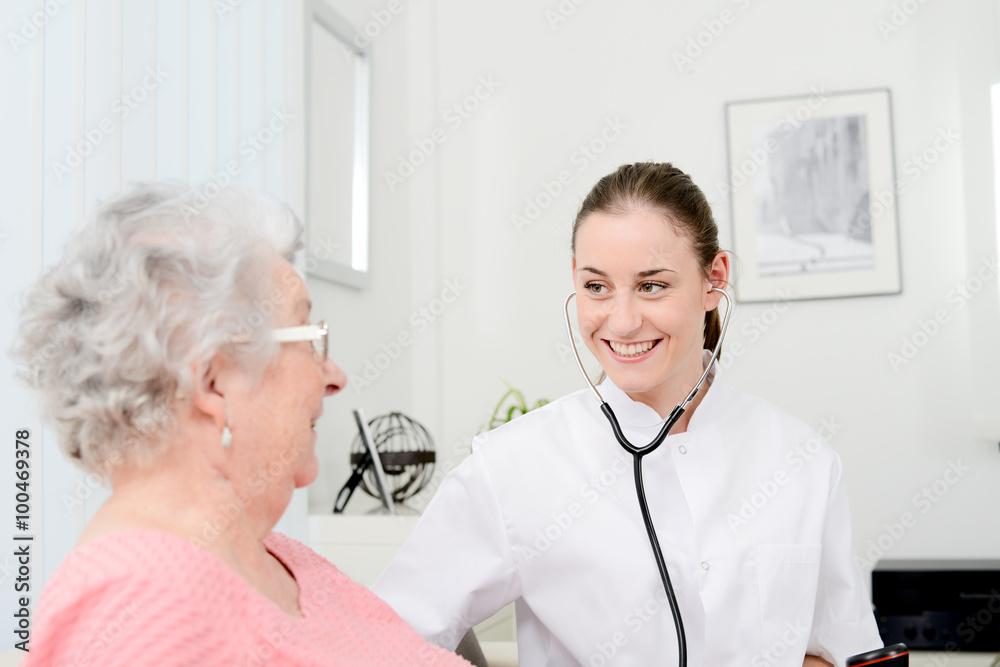 cheerful young doctor giving medical health care to an elderly woman at home cheerful young doctor giving medical health care to an elderly woman at home