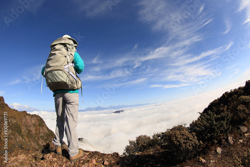 young woman backpacker hiking on mountain peak