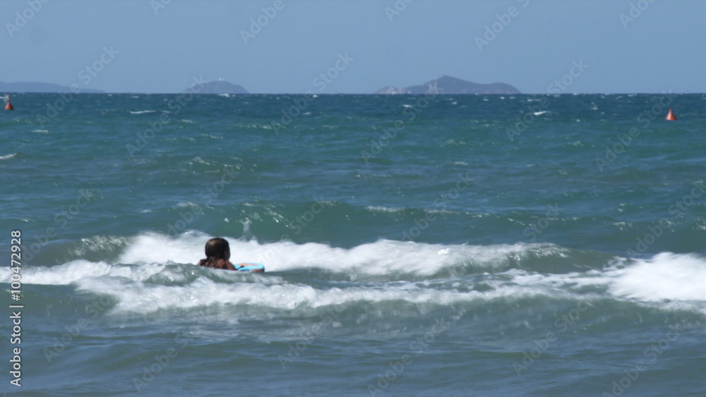 Woman riding the waves on a boogie board, in Italy. Woman riding the waves on a boogie board, in Italy.