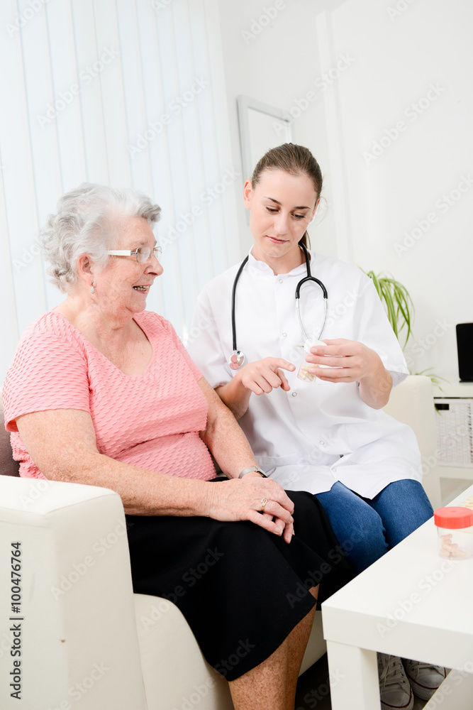 cheerful young nurse giving drug prescription to an elderly woman at home cheerful young nurse giving drug prescription to an elderly woman at home