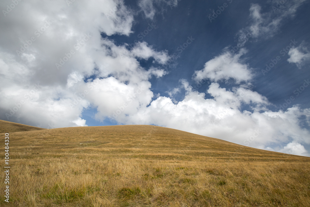 Autumn blue sky with white clouds and mountains on the yellowed