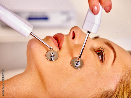 Young woman receiving electric galvanic anti-aging face spa massage at beauty salon.  photo