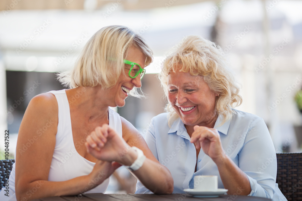 Senior women laughing in street cafe Senior women laughing in street cafe