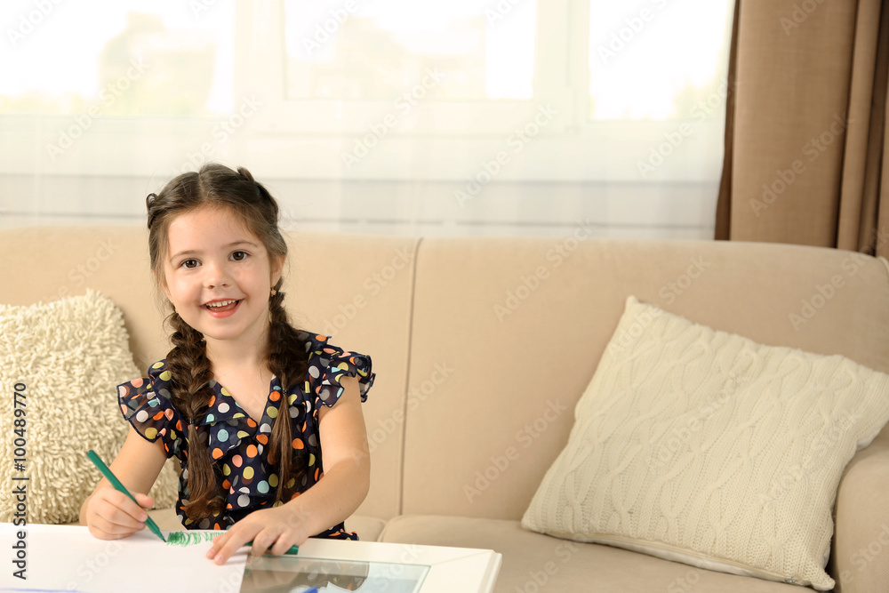 Cute little girl drawing picture on home interior background
