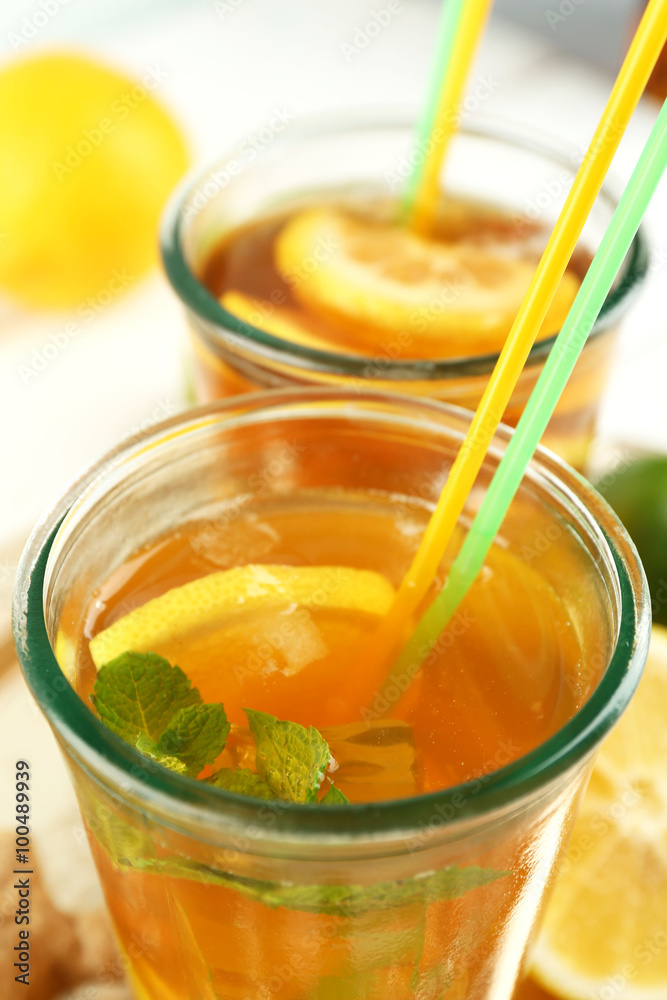 Iced tea with lemon on light wooden background