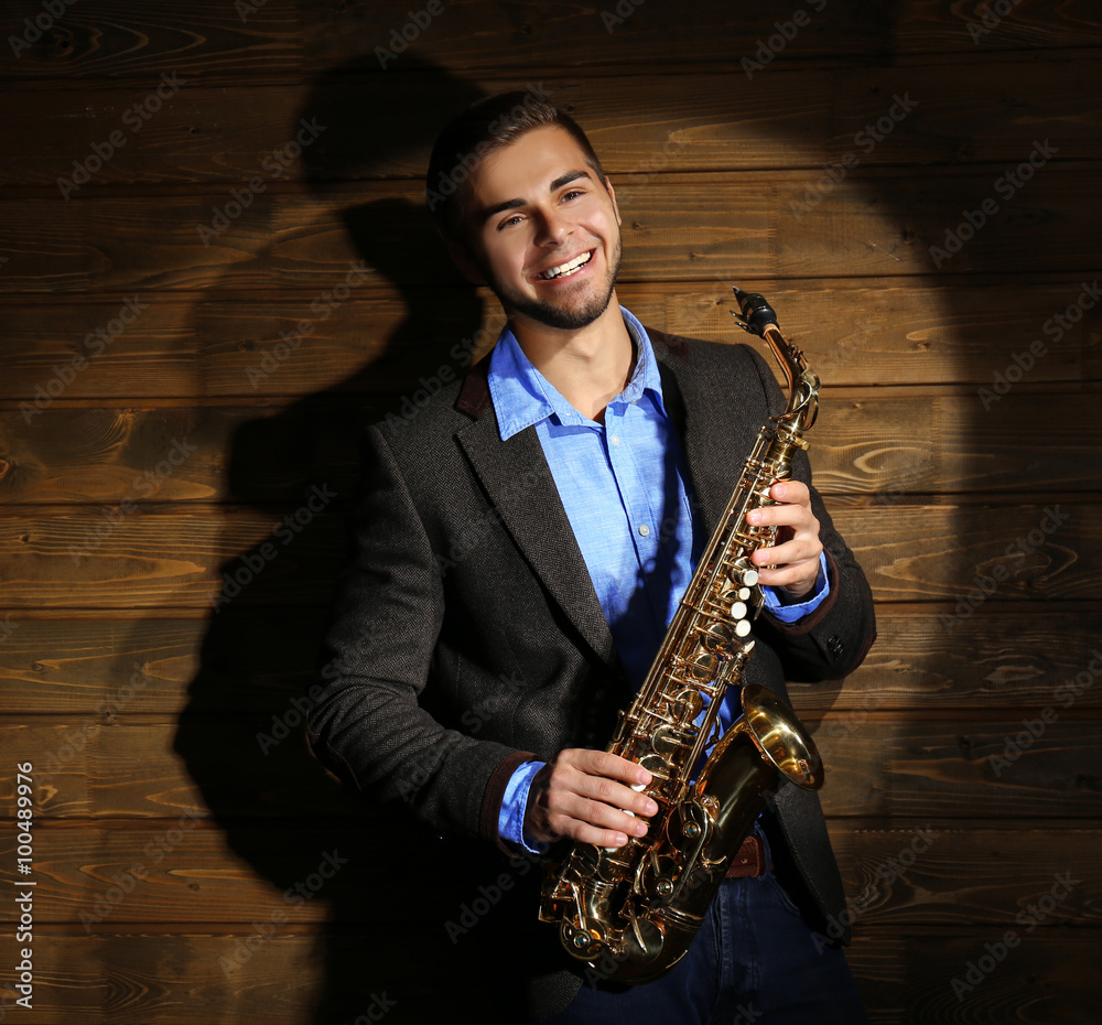 Fototapeta premium Elegant saxophonist plays jazz on wooden background