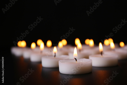 Alight candles in a row on black background