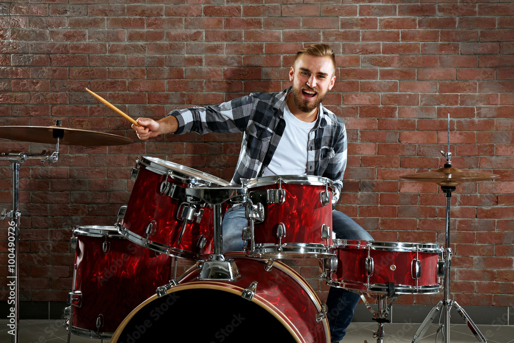Fototapeta premium Musician playing the drums on brick wall background