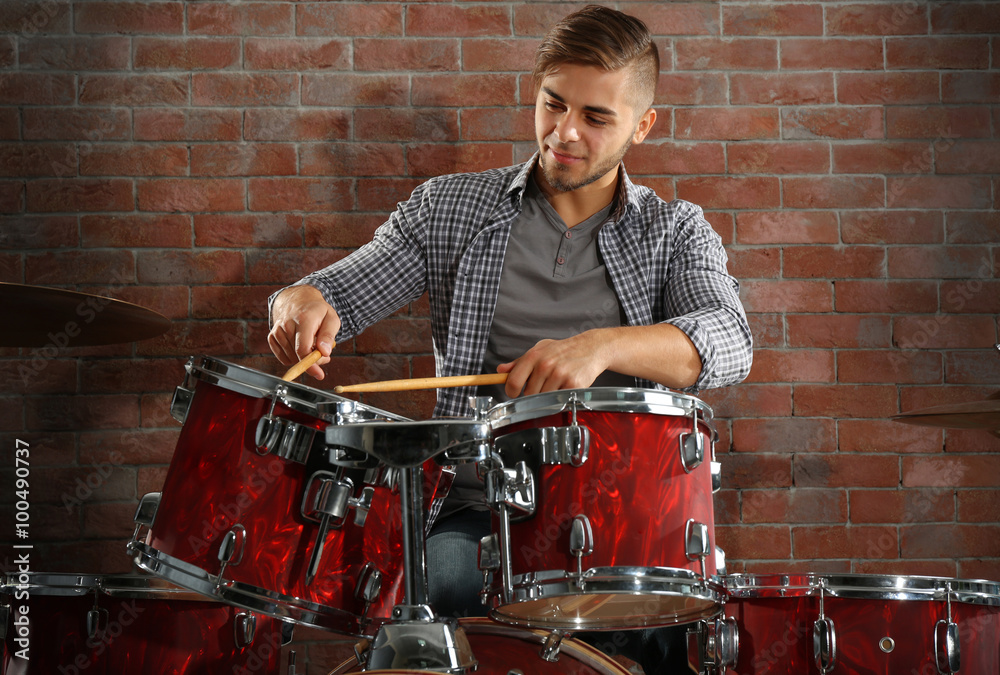 Musician playing the drums on brick wall background Musician playing the drums on brick wall background