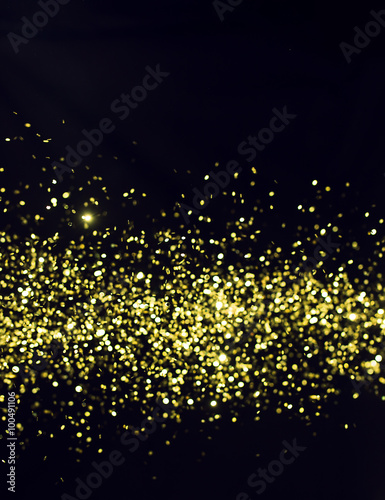 Photo of golden glitter on a black background. Golden explosion