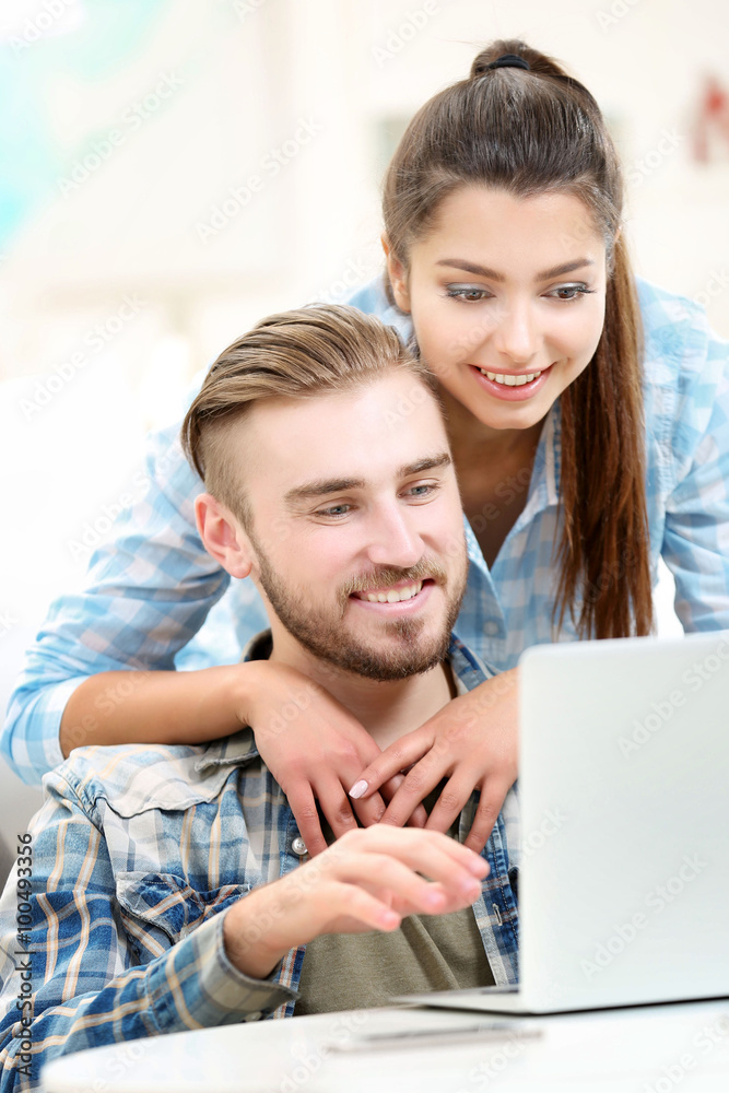 Happy couple sitting at the table and working with a laptop Happy couple sitting at the table and working with a laptop