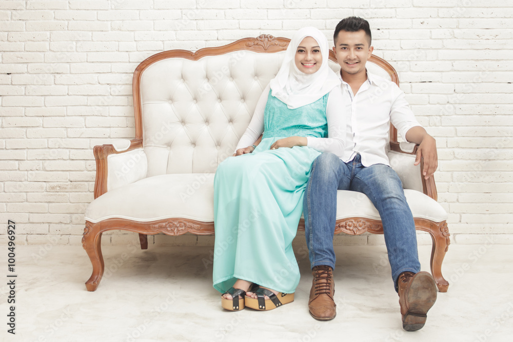 asian couple sitting on sofa while looking at camera asian couple sitting on sofa while looking at camera