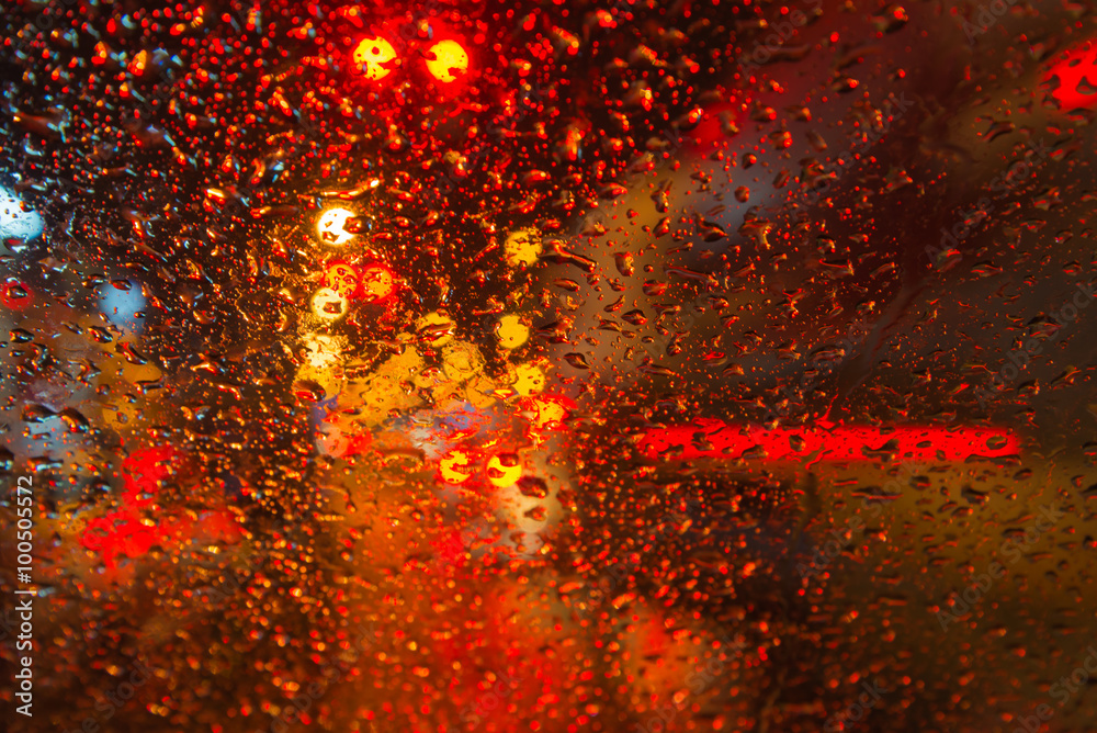 Rain drop with street colorful traffic lights at night blur bokeh abstract background 
