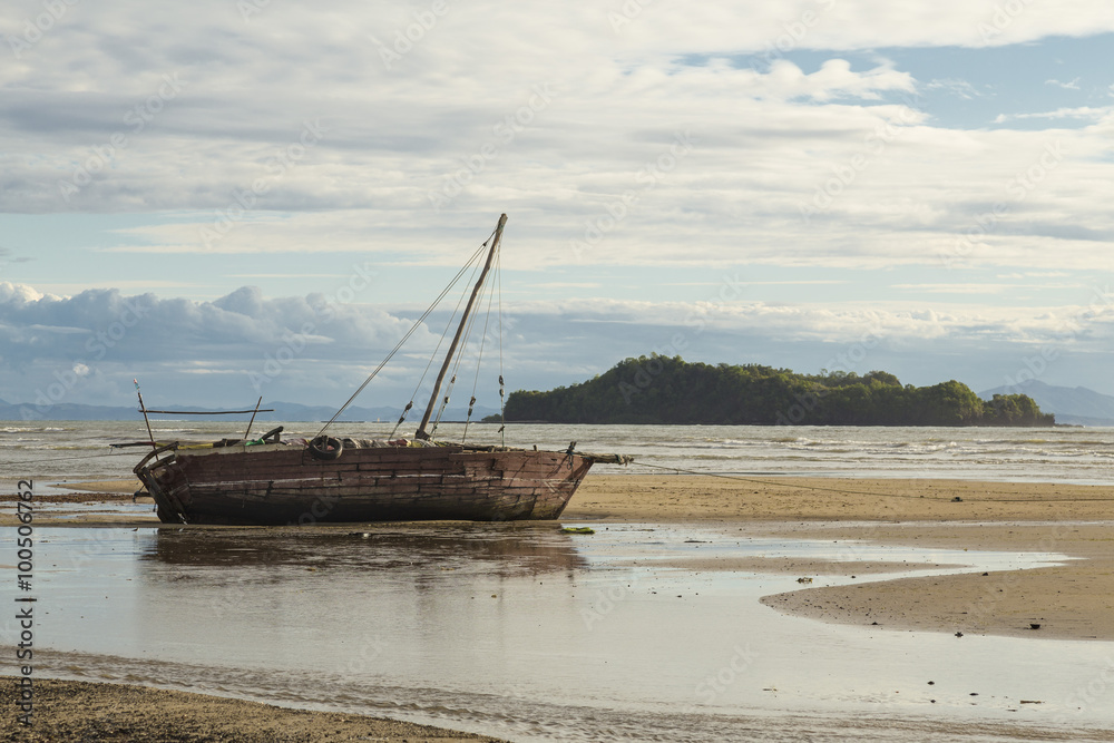 Nautical ship stranded on a beach under a blue cloudy sky in Madagascar
