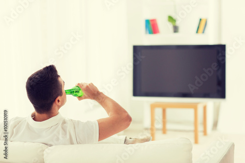 Fototapeta Naklejka Na Ścianę i Meble -  man watching tv and drinking beer at home
