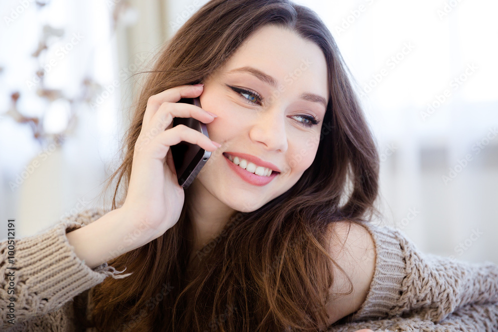 Cheerful beautiful woman talking on mobile phone at home Cheerful beautiful woman talking on mobile phone at home