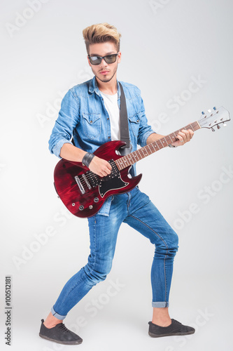 artist playing guitar in studio background while posing