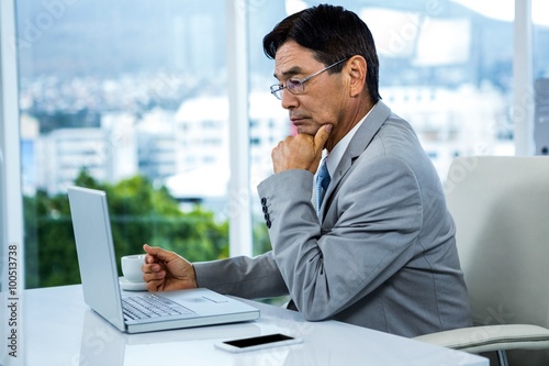 Thoughtful businessman using laptop