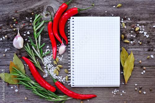 Vegetables and seasonings with open notebook for recipes on a wooden background