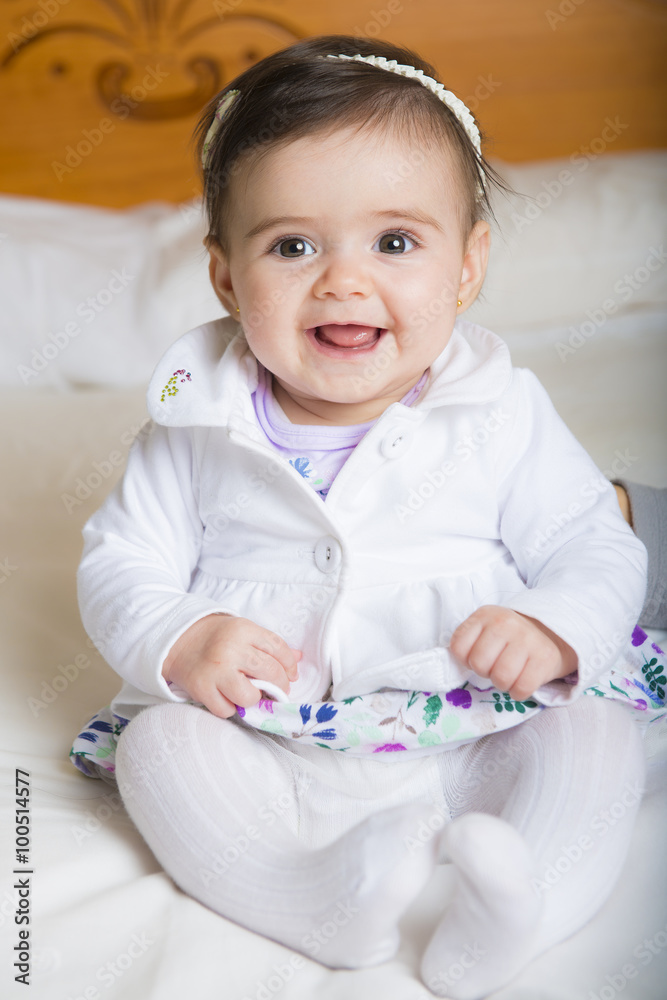 Bebé niña simpática sonriente sentada sobre una colcha de cama suave Stock  Photo