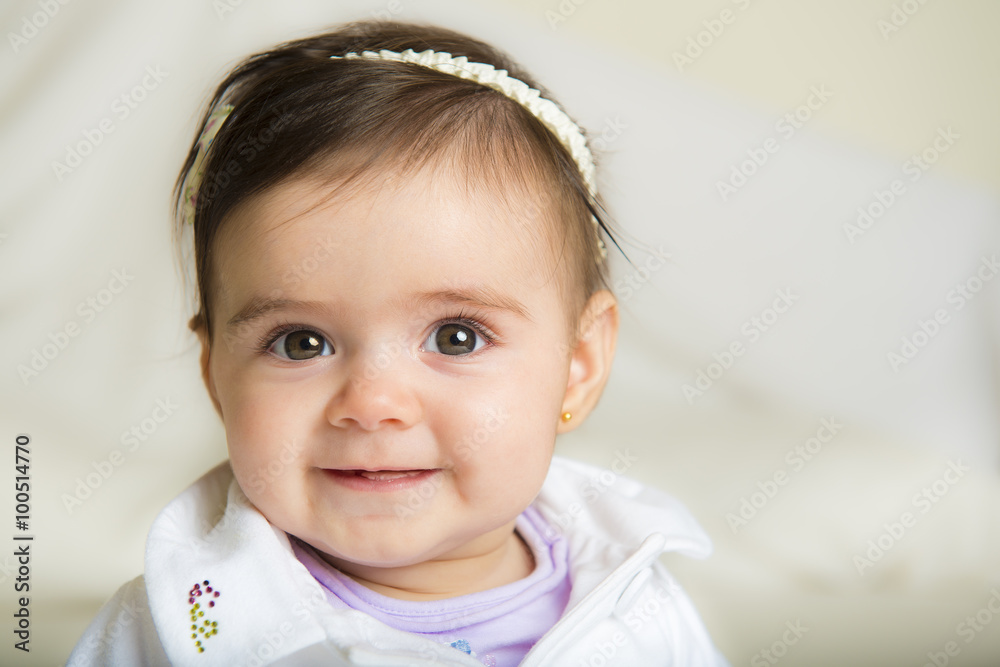 Bebé niña simpática sonriente sentada sobre una colcha de cama suave Bebé niña simpática sonriente sentada sobre una colcha de cama suave