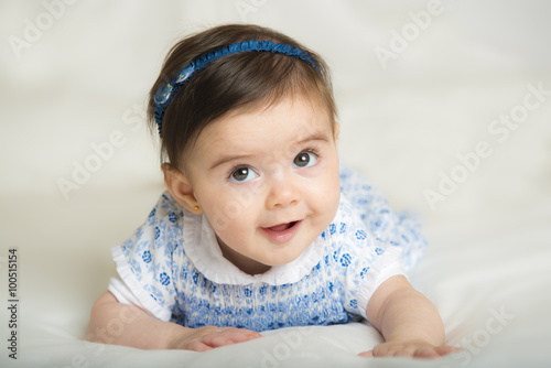 Bebé niña con bonita sonrisa gateando por primera vez sobre una cama photo