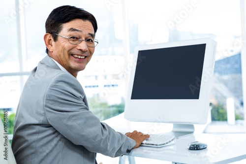 Smiling businessman using his computer 