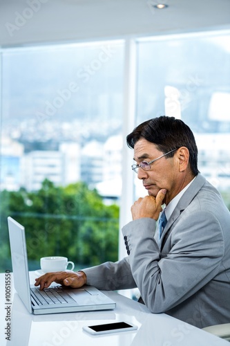 Thoughtful businessman using laptop