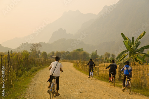 Children cycling, Sunset at limestone mountains of Vang Vieng, Laos photo