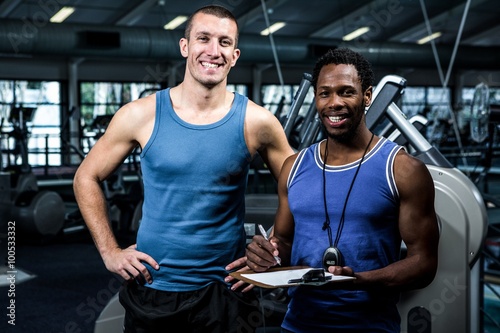 Muscular man with trainer smiling at camera 