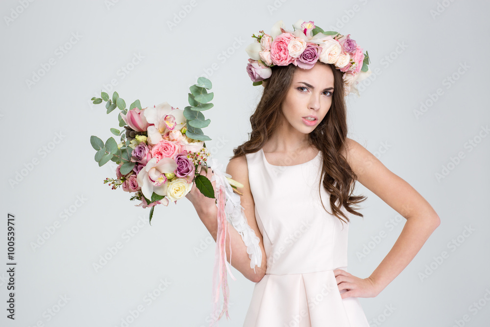 Attractive irritated woman in rose wreath showing bouquet of flowers Attractive irritated woman in rose wreath showing bouquet of flowers