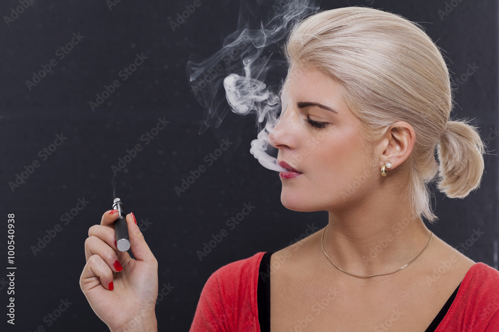 Obraz premium Stylish blond woman smoking an e-cigarette
