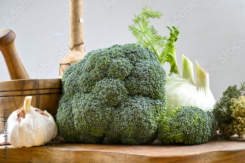 Green broccoli and white fennel on cutting board from olive wood on white background photo