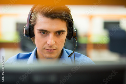 Tablou pe pânză Young customer service operator talking on headset, smiling.
